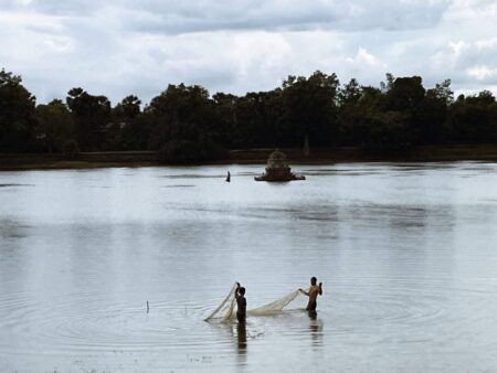 people stretching fishing nets in moat at angkor